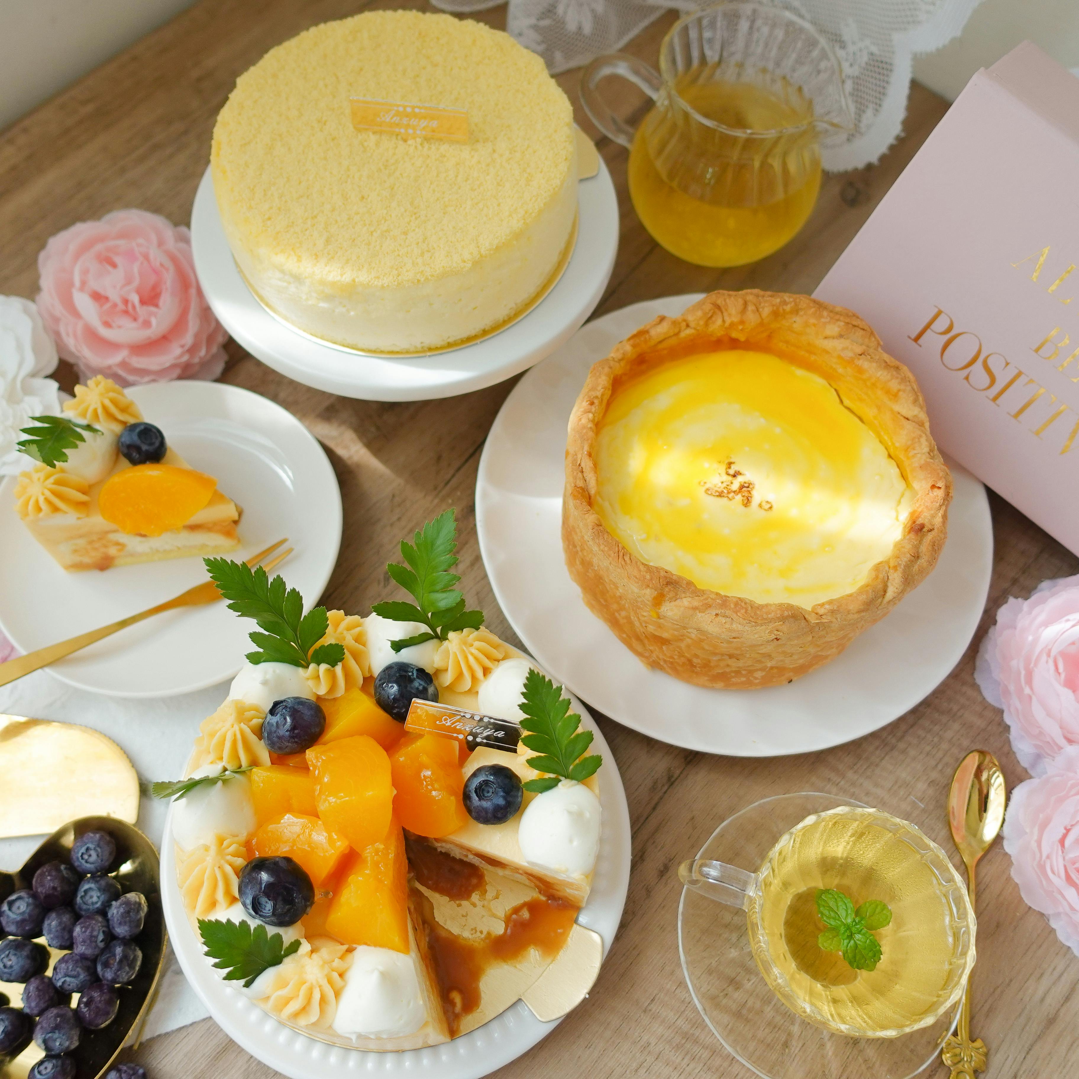 A delightful assortment of cheesecakes and pastries with fruits and tea on a wooden table.